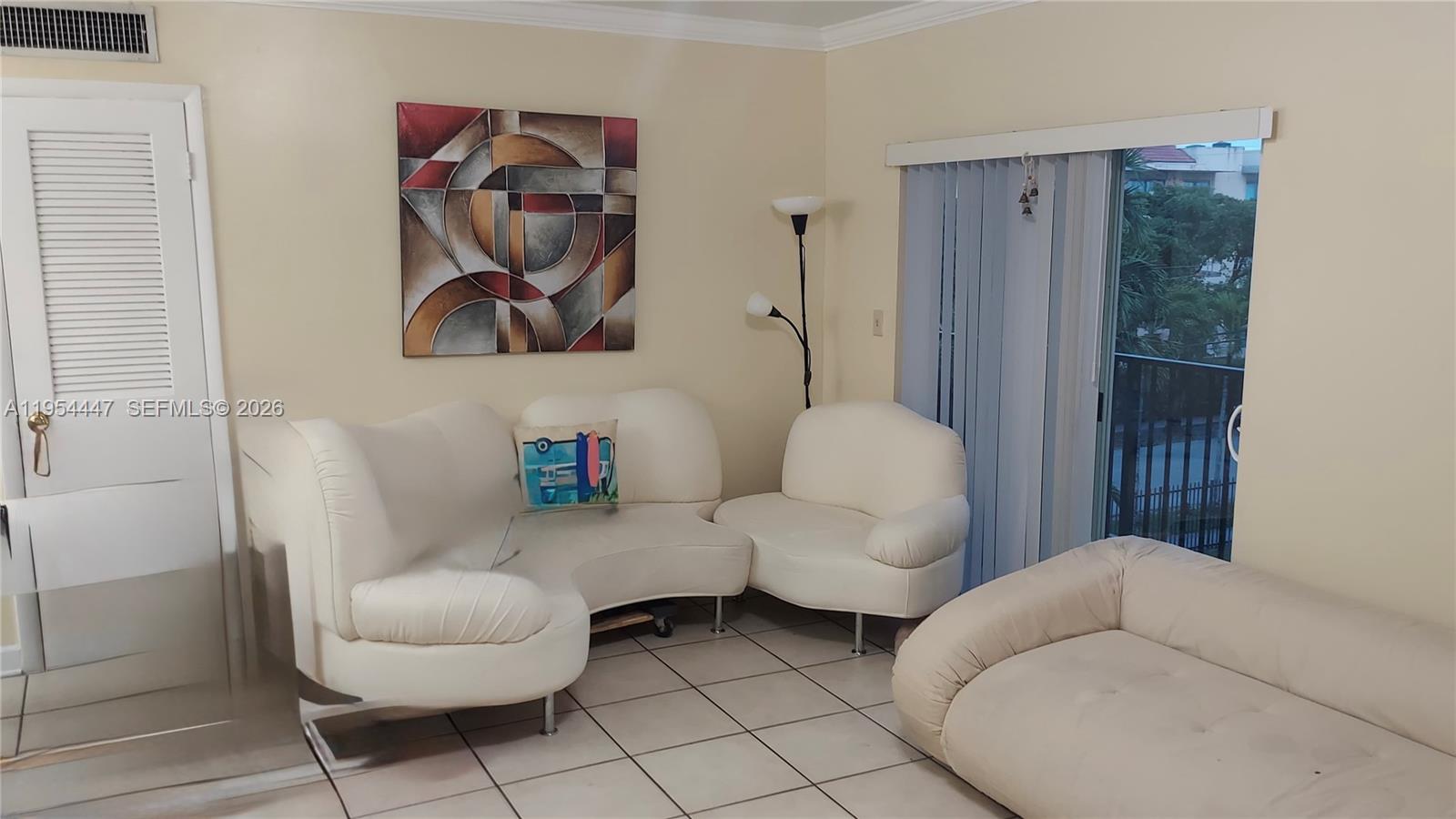 A living room features white curved sofas, tile flooring, and a large abstract wall painting — 900 SW 84th Ave # 301E, Miami FL 33144, MIAMI, FL