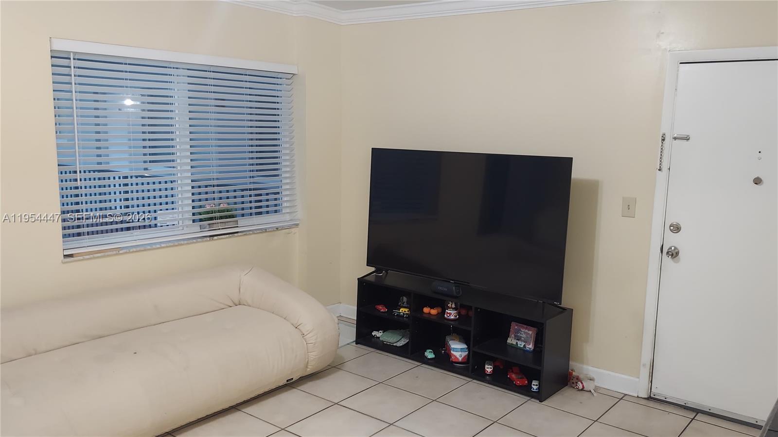 A living room features a white sofa, a large television on a black stand, and tile flooring — 900 SW 84th Ave # 301E, Miami FL 33144, MIAMI, FL