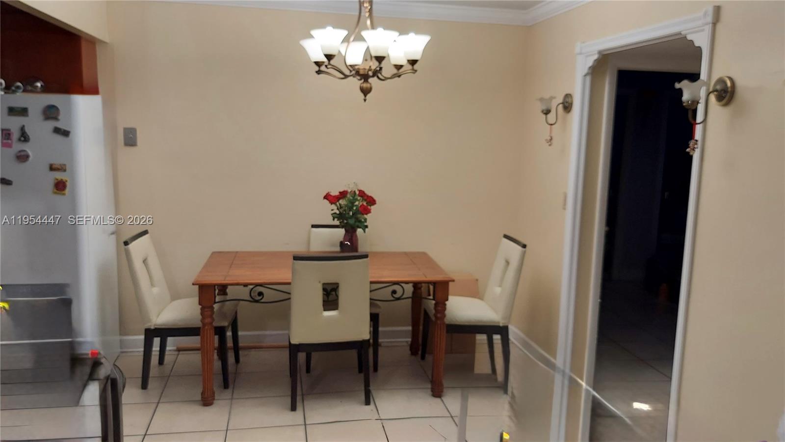 A dining area features a wooden table, four chairs, and a chandelier on tiled floors — 900 SW 84th Ave # 301E, Miami FL 33144, MIAMI, FL