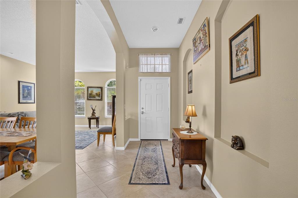 A tiled entryway features a white front door, a wooden console table, and wall niches — 11115 SILVER DANCER DRIVE, RIVERVIEW, FL