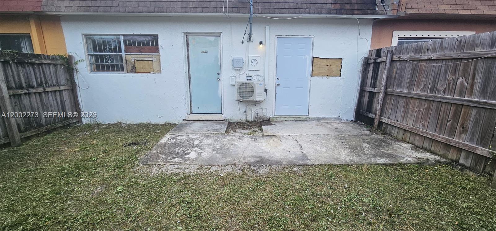 The exterior of a white building features two doors, a window, and a concrete patio — 3932 NW 207th St Rd, Miami Gardens FL 33055, MIAMI GARDENS, FL