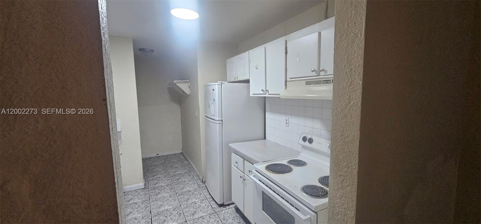 A galley-style kitchen features white cabinets, a white refrigerator, and a white electric range — 3932 NW 207th St Rd, Miami Gardens FL 33055, MIAMI GARDENS, FL