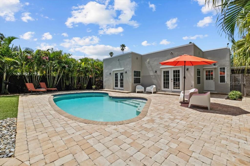 A backyard features a swimming pool, a paved patio, and a single-story house exterior — 219 N MISSOURI AVENUE, CLEARWATER, FL