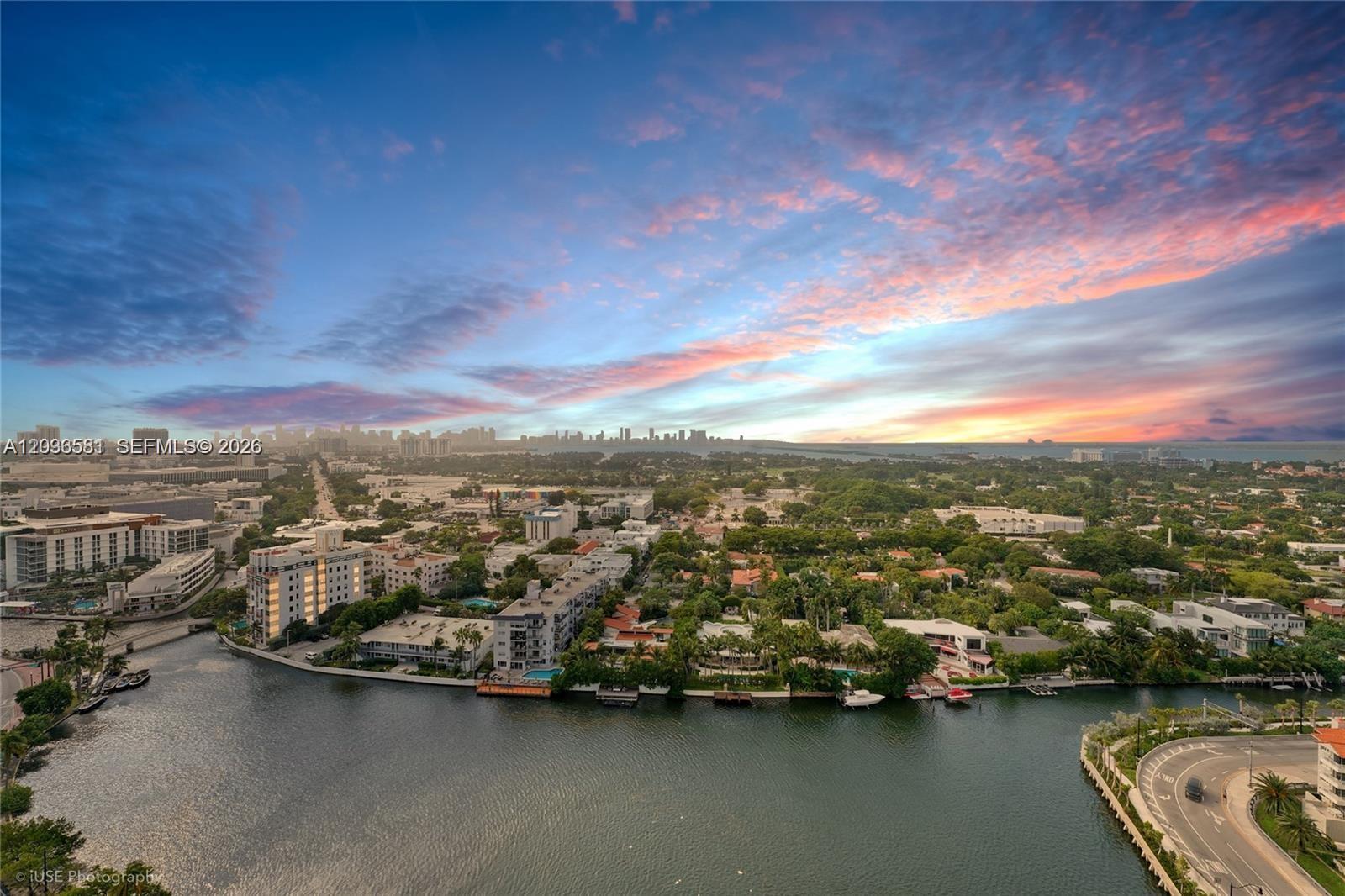 An aerial view shows a waterfront residential area with buildings, trees, and a winding road — 2555 Collins Ave # 2204, Miami Beach FL 33140, MIAMI BEACH, FL