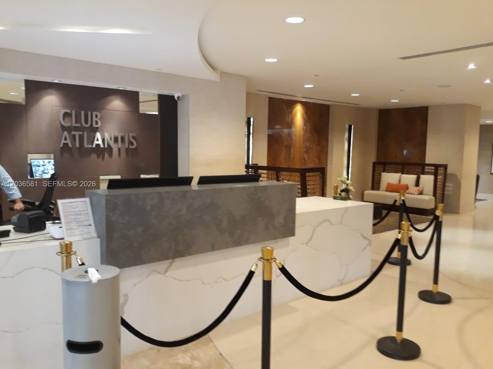 A modern reception desk with marble and stone finishes stands in a building lobby — 2555 Collins Ave # 2204, Miami Beach FL 33140, MIAMI BEACH, FL