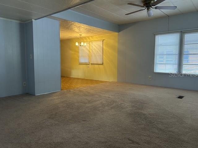 A carpeted living room opens into a dining area with a chandelier and yellow walls — 16815 SE 101ST COURT ROAD, SUMMERFIELD, FL