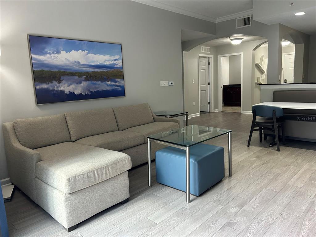 A living room features a gray sectional sofa, a glass coffee table, and wood-look flooring — 14501 GROVE RESORT AVENUE UNIT 1409, WINTER GARDEN, FL