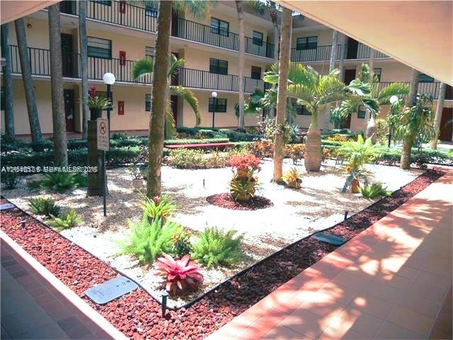 A landscaped courtyard with palm trees and gravel beds sits between multi-story apartment buildings — 10845 SW 112th Ave # 211, Miami FL 33176, MIAMI, FL