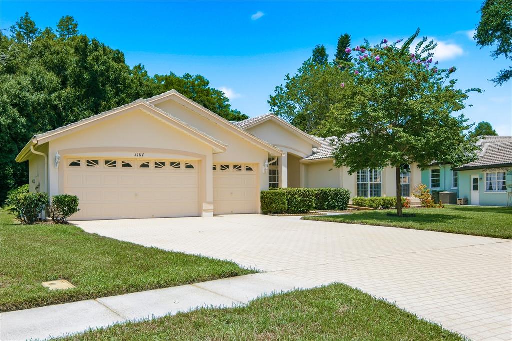 A single-story house with a beige exterior, a three-car garage, and a paved driveway — 3187 STERLING STREET, TARPON SPRINGS, FL