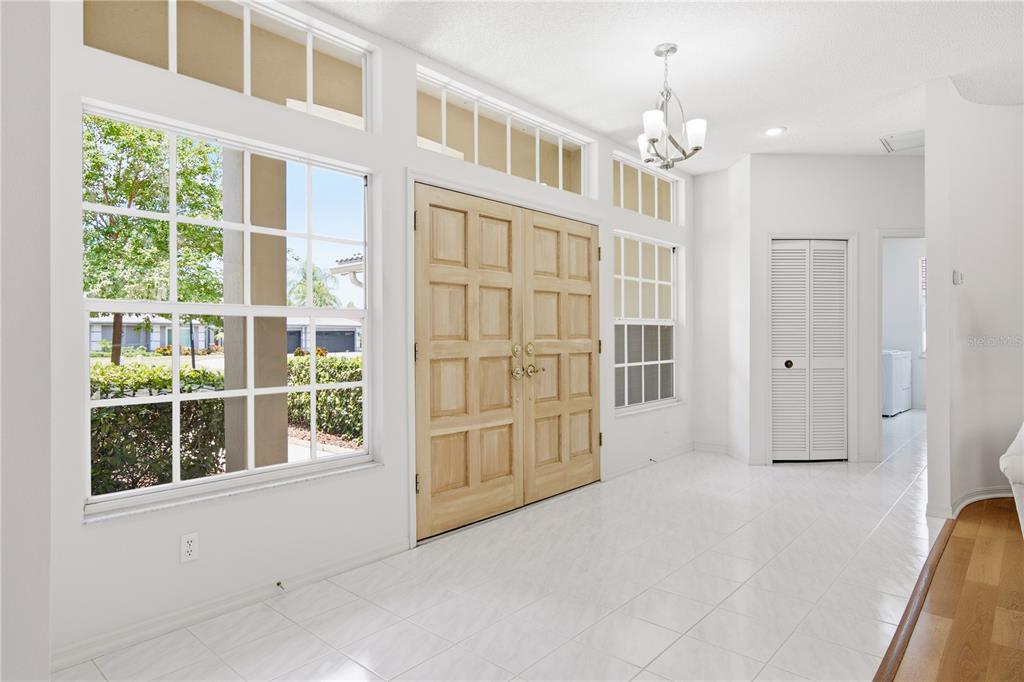 A bright entryway features white tile floors, double wooden doors, and large windows with transoms — 3187 STERLING STREET, TARPON SPRINGS, FL