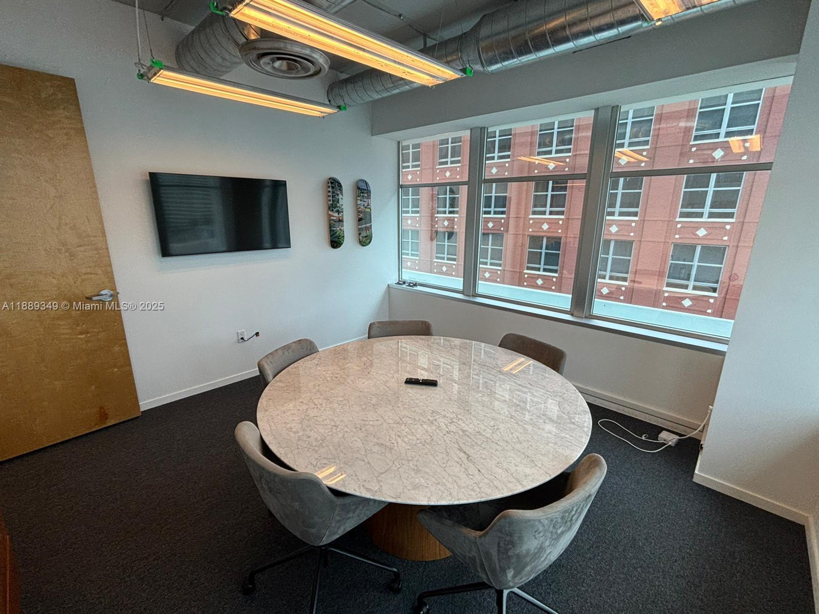 A conference room features a round marble table, gray chairs, and a wall-mounted television — 14 NE 1st Ave, Miami FL 33132, MIAMI, FL