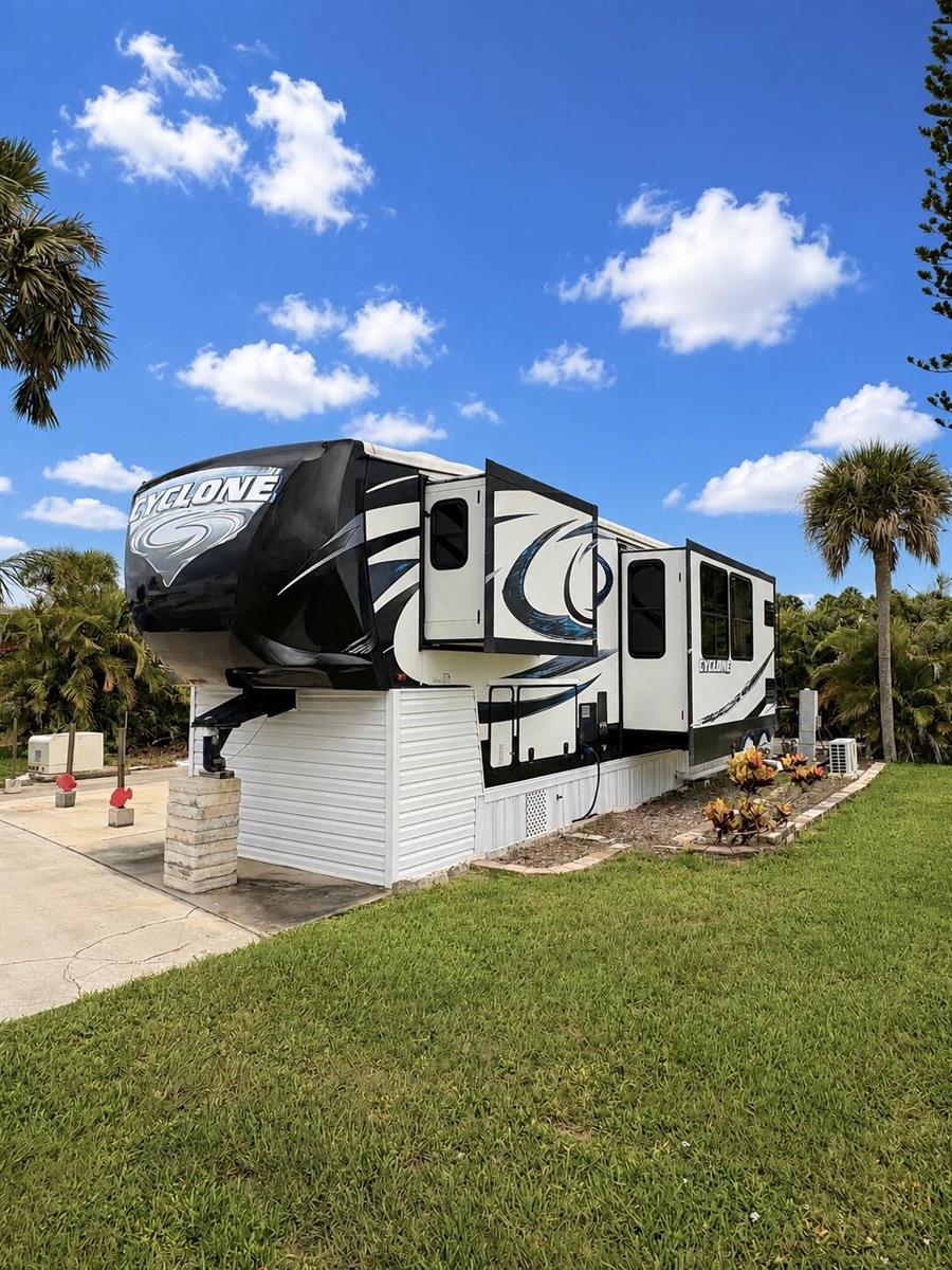 A Cyclone fifth-wheel RV is parked on a concrete pad surrounded by palm trees — 14130 SE 126th Boulevard, Okeechobee FL 34974, OKEECHOBEE, FL