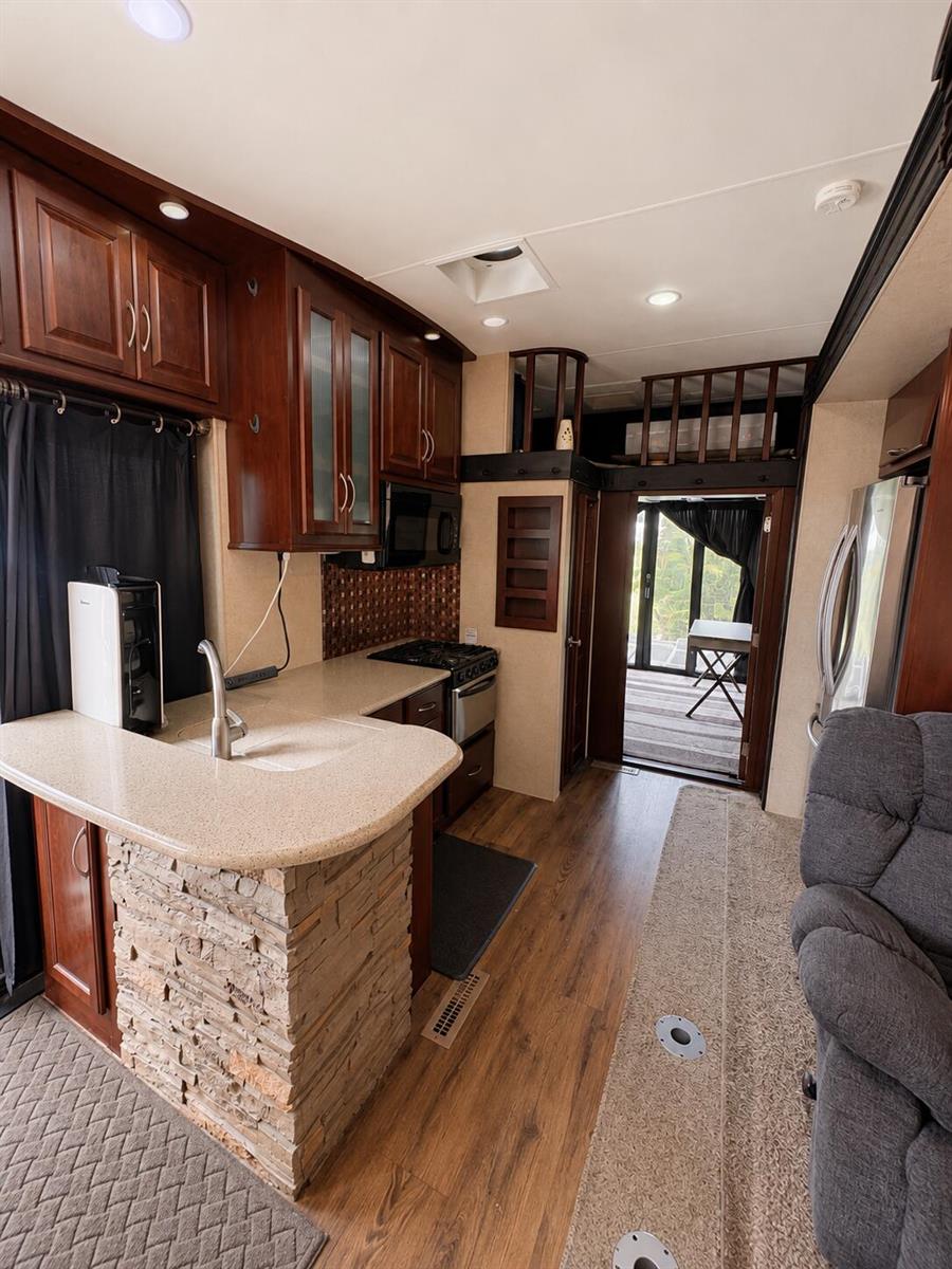 A kitchen with stone-accented island, dark wood cabinetry, and a view into a rear deck — 14130 SE 126th Boulevard, Okeechobee FL 34974, OKEECHOBEE, FL