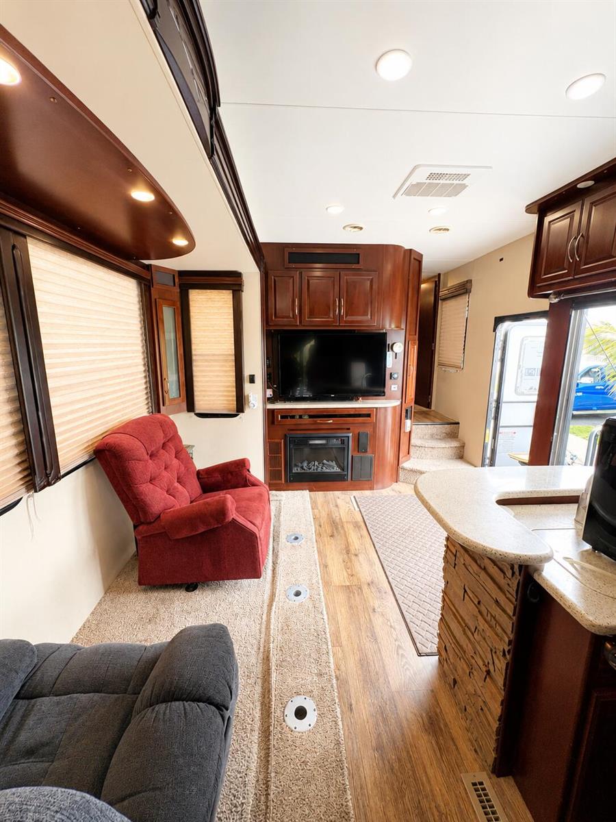 The interior of an RV features a living area with a red recliner and fireplace — 14130 SE 126th Boulevard, Okeechobee FL 34974, OKEECHOBEE, FL