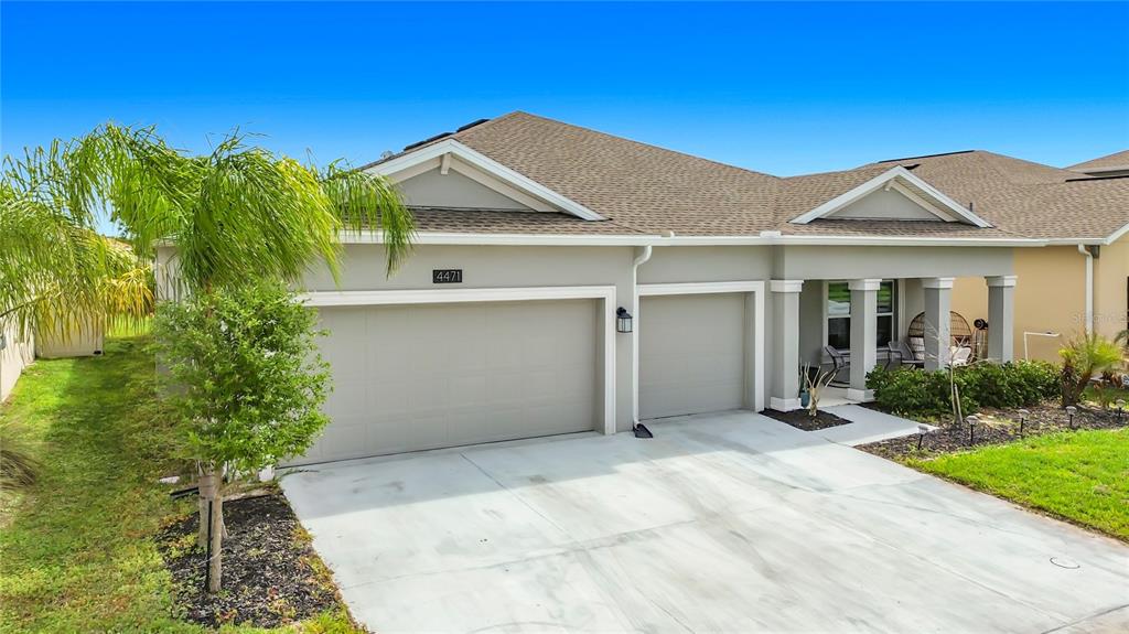 A single-story house exterior features a three-car garage, a covered entryway, and a palm tree — 4471 HOLSTEIN STREET, ST CLOUD, FL