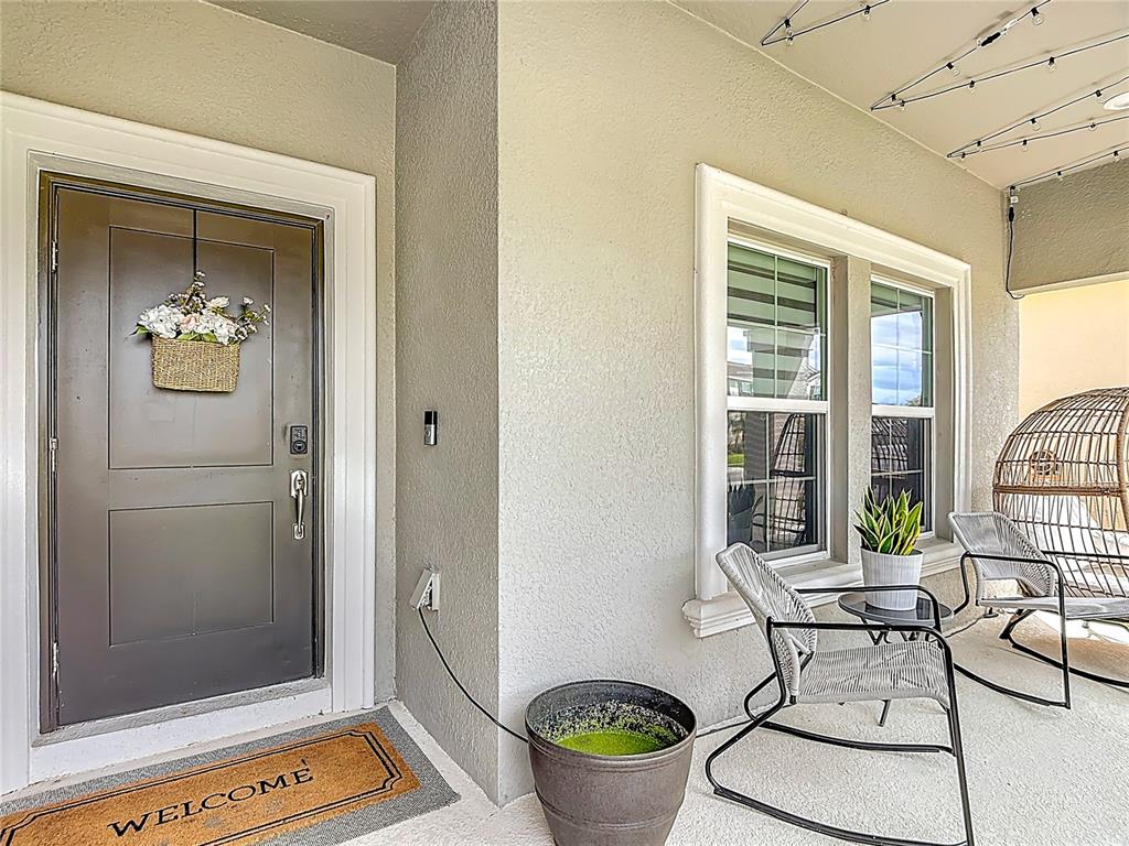 A covered front porch features a dark door, two windows, rocking chairs, and a planter — 4471 HOLSTEIN STREET, ST CLOUD, FL