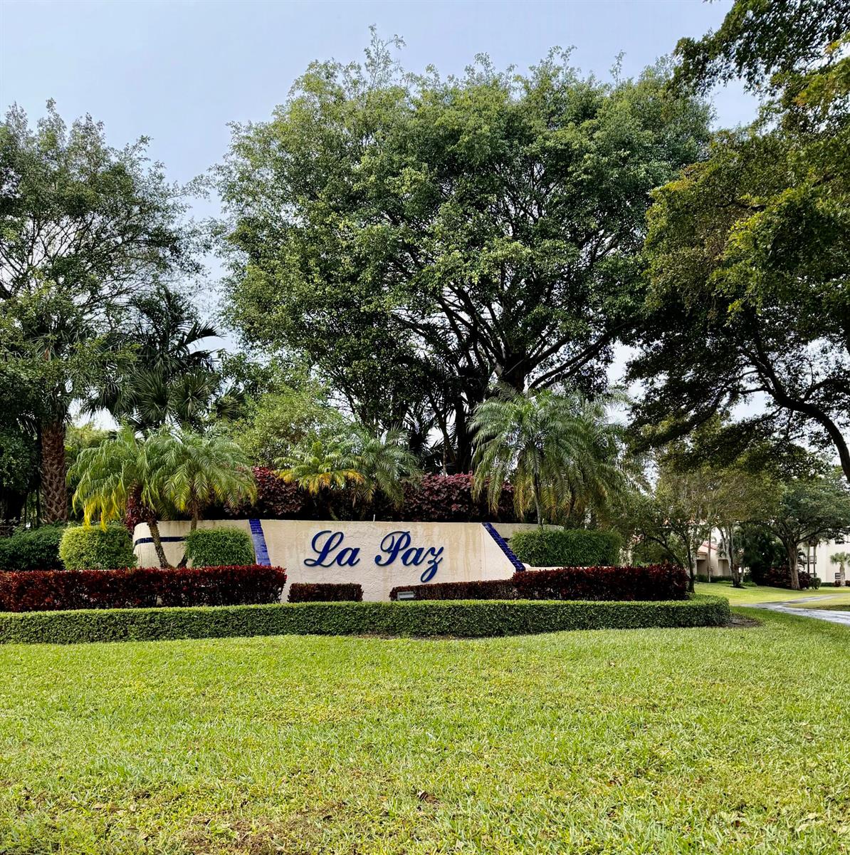 A landscaped entrance sign for La Paz features a beige wall with blue accents and palm trees — 7535 La Paz Boulevard # 307, Boca Raton FL 33433, BOCA RATON, FL