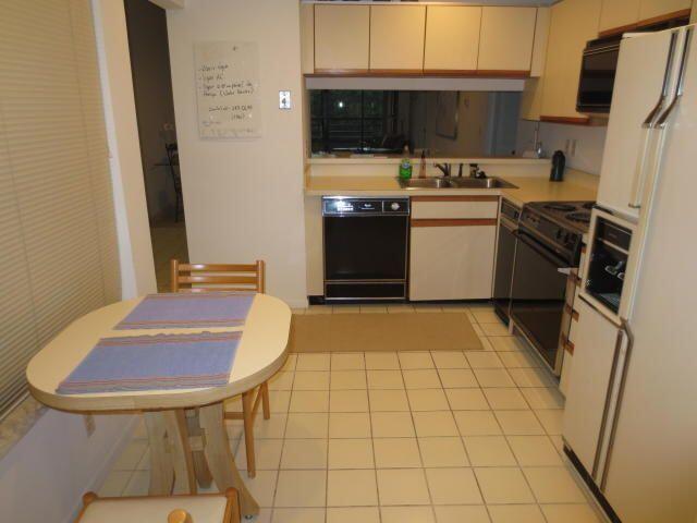 A kitchen with white cabinets, black appliances, a tile floor, and a small dining table — 7535 La Paz Boulevard # 307, Boca Raton FL 33433, BOCA RATON, FL