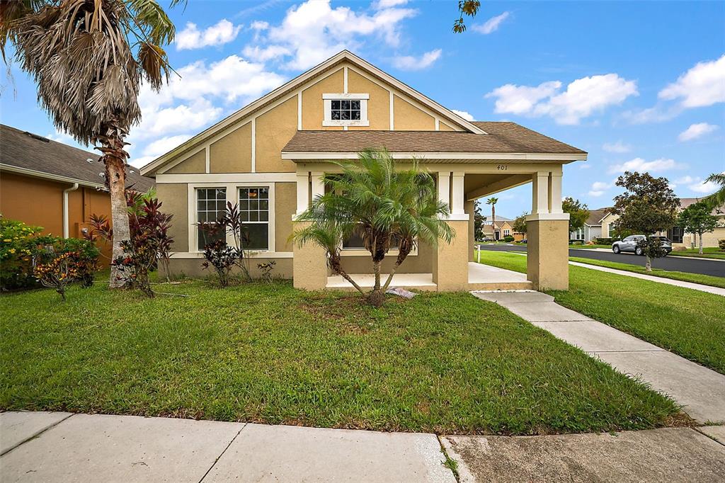 A single-story house with a tan stucco exterior, a front porch, and a palm tree — 401 GRASSY KEY WAY, GROVELAND, FL