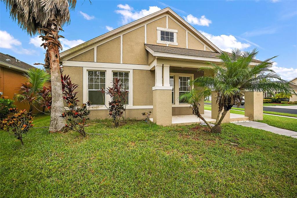A single-story house with tan stucco siding, a front porch, and a palm tree — 401 GRASSY KEY WAY, GROVELAND, FL