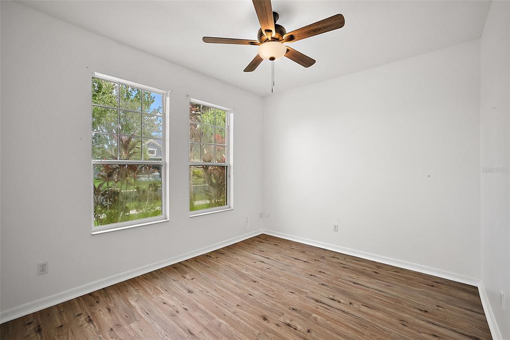 An empty room with wood-look flooring, white walls, a ceiling fan, and two windows — 401 GRASSY KEY WAY, GROVELAND, FL