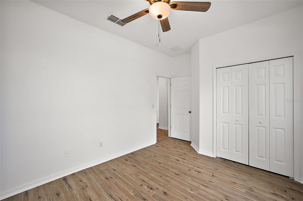A bedroom with white walls, wood-look flooring, a ceiling fan, and a white closet — 401 GRASSY KEY WAY, GROVELAND, FL