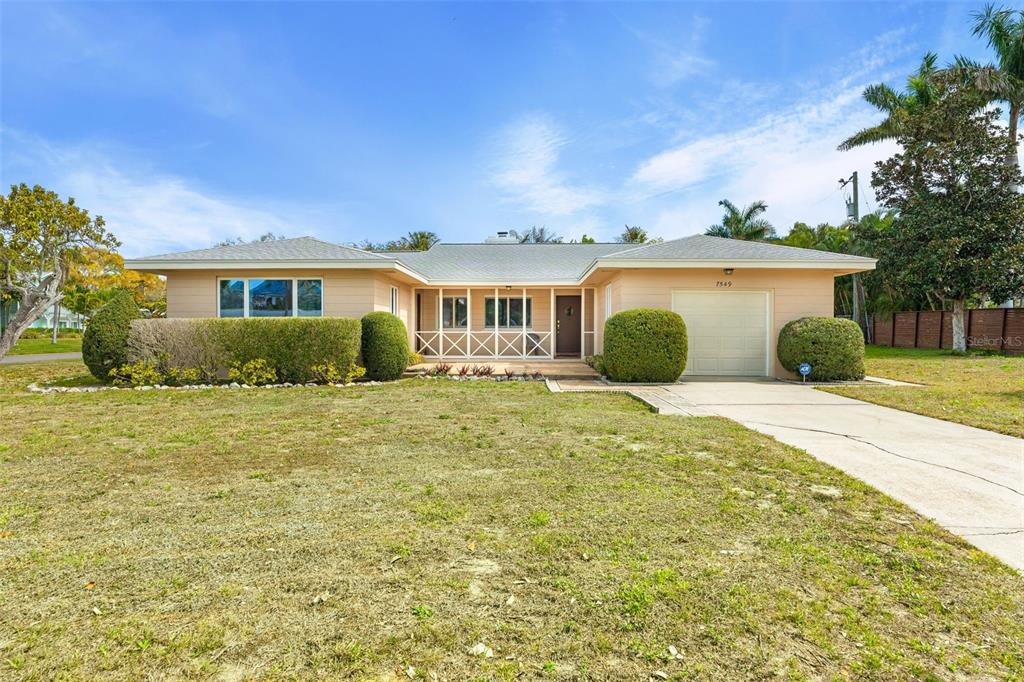 A single-story house with a beige exterior, a one-car garage, and a screened front porch — 7549 WESTMORELAND DRIVE, SARASOTA, FL