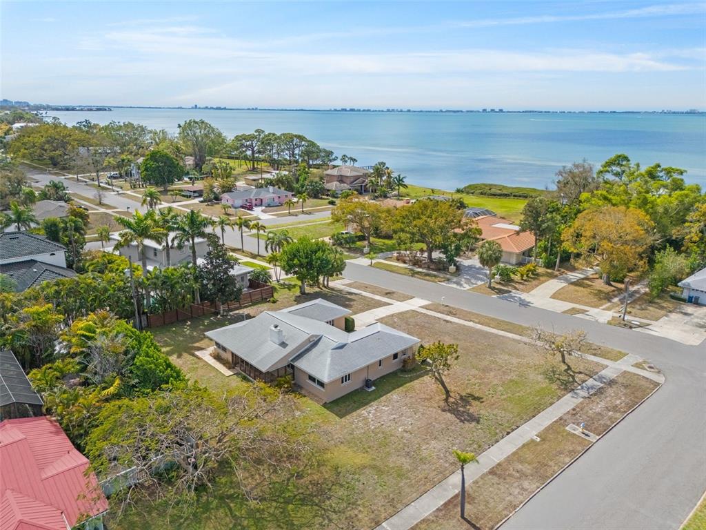 An aerial view shows a single-story house with a gray roof near a large body of water — 7549 WESTMORELAND DRIVE, SARASOTA, FL