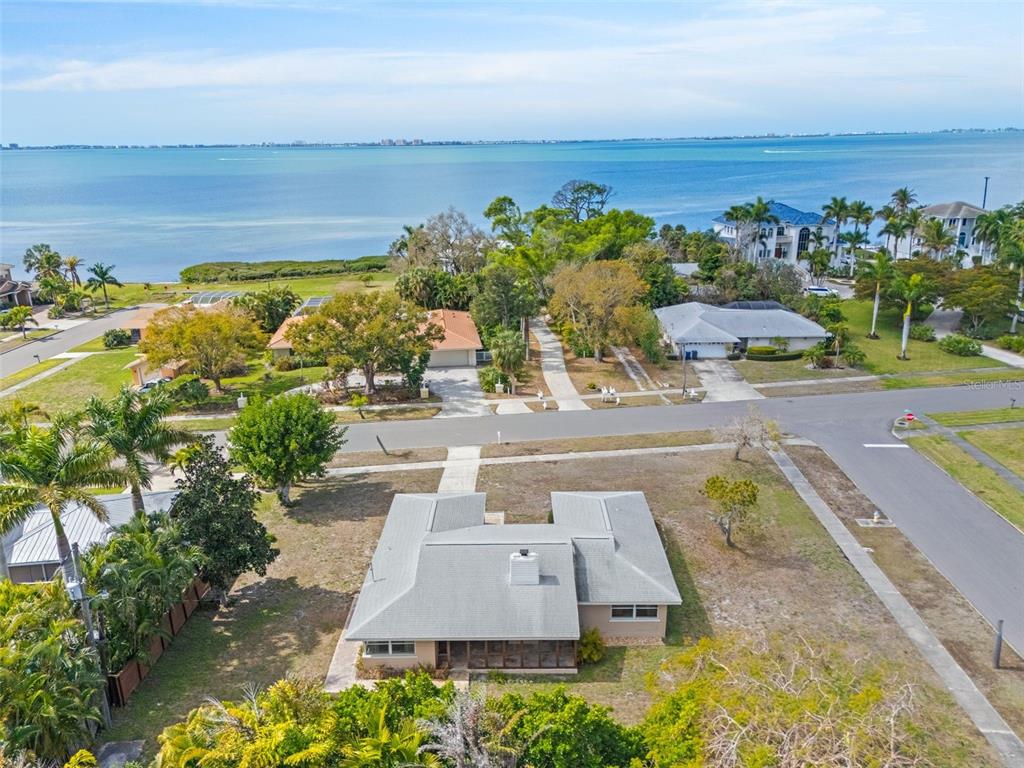 An aerial view shows a single-story house with a gray roof near a large body of water — 7549 WESTMORELAND DRIVE, SARASOTA, FL