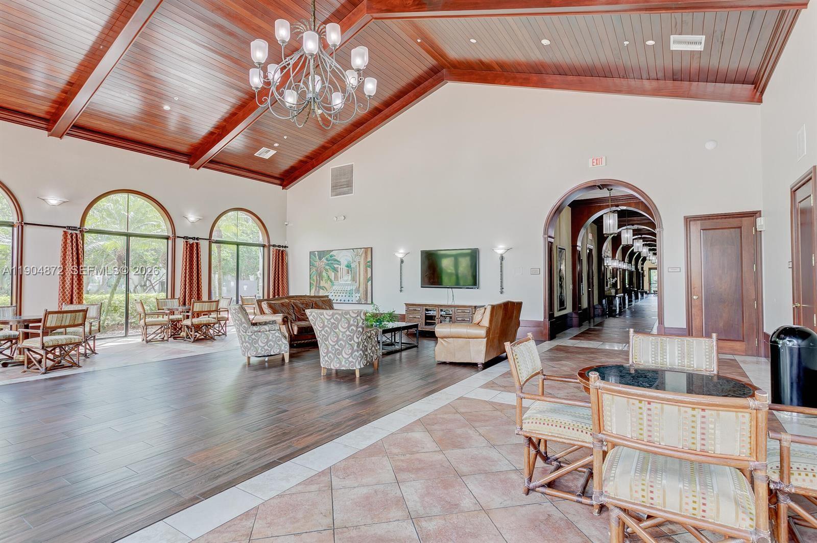 A spacious clubhouse lounge features a vaulted wood ceiling, chandelier, and mixed tile and wood flooring — 9042 Dupont Pl, Wellington FL 33414, WELLINGTON, FL