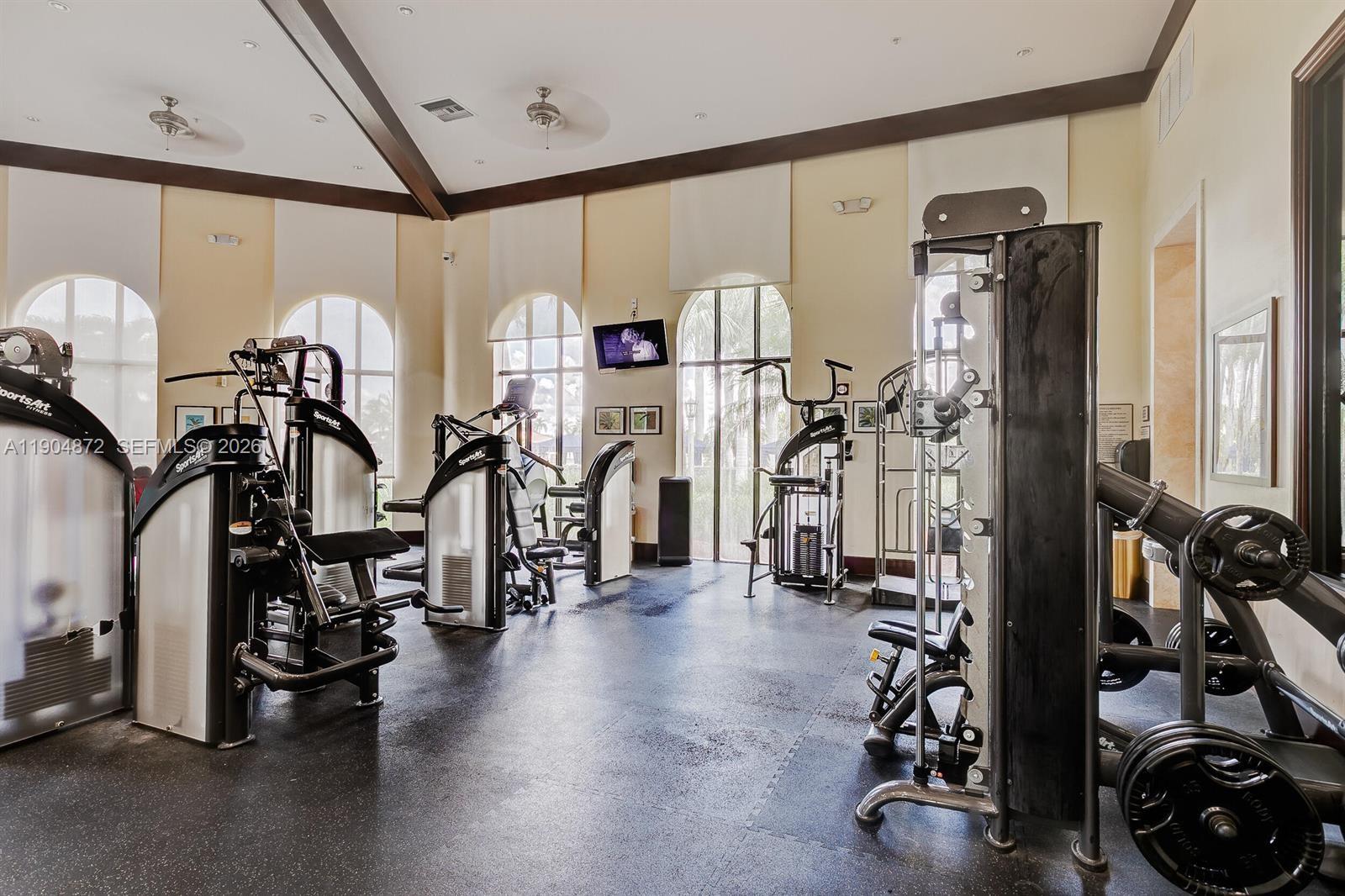 A gym with multiple exercise machines, high ceilings, and large arched windows — 9042 Dupont Pl, Wellington FL 33414, WELLINGTON, FL