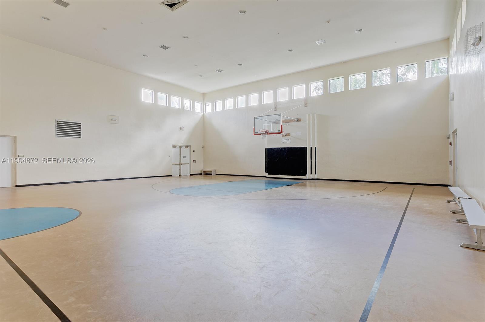 An indoor basketball court features high ceilings, light-colored walls, and a basketball hoop — 9042 Dupont Pl, Wellington FL 33414, WELLINGTON, FL