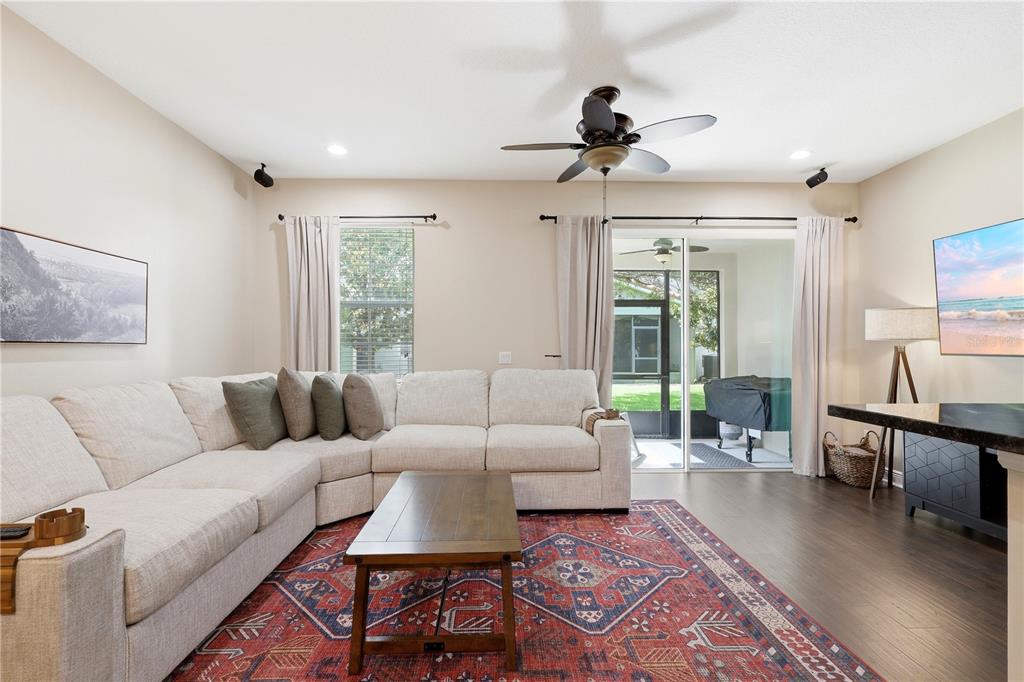 A living room features a large sectional sofa, a wooden coffee table, and a patterned rug — 5415 VIA APPIA WAY, SANFORD, FL