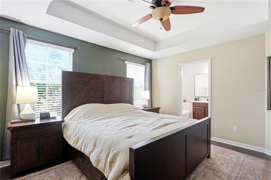 A bedroom features a dark wood bed frame, an accent wall, and an attached bathroom — 5415 VIA APPIA WAY, SANFORD, FL