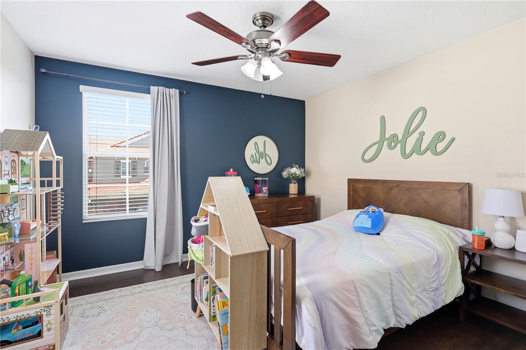 A bedroom features a dark blue accent wall, a wooden bed, and a dollhouse bookshelf — 5415 VIA APPIA WAY, SANFORD, FL