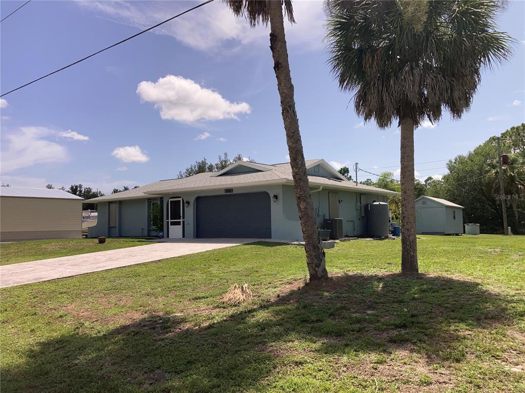A light blue single-story house with a garage and two palm trees in the yard — 185 CHAMPION STREET, PORT CHARLOTTE, FL
