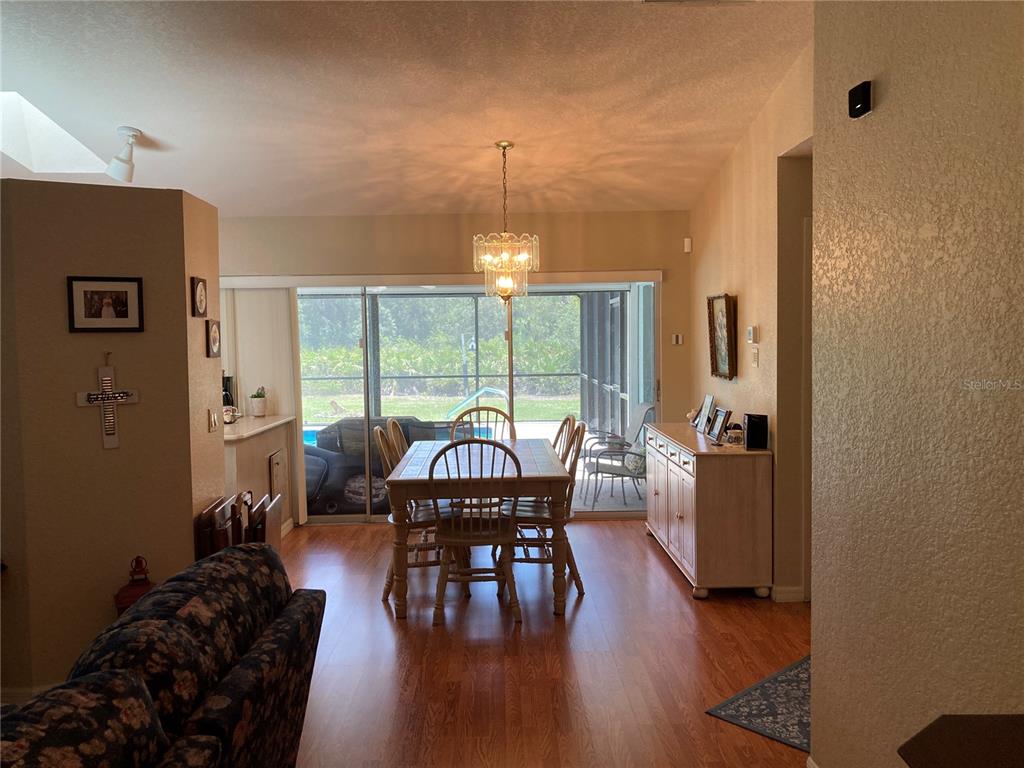 A dining area with a wooden table and chairs sits before sliding glass patio doors — 185 CHAMPION STREET, PORT CHARLOTTE, FL