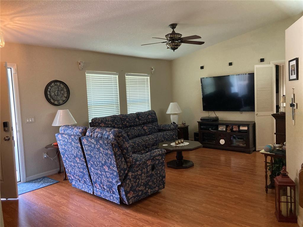 A living room features a floral sofa, a television on a console, and wood flooring — 185 CHAMPION STREET, PORT CHARLOTTE, FL
