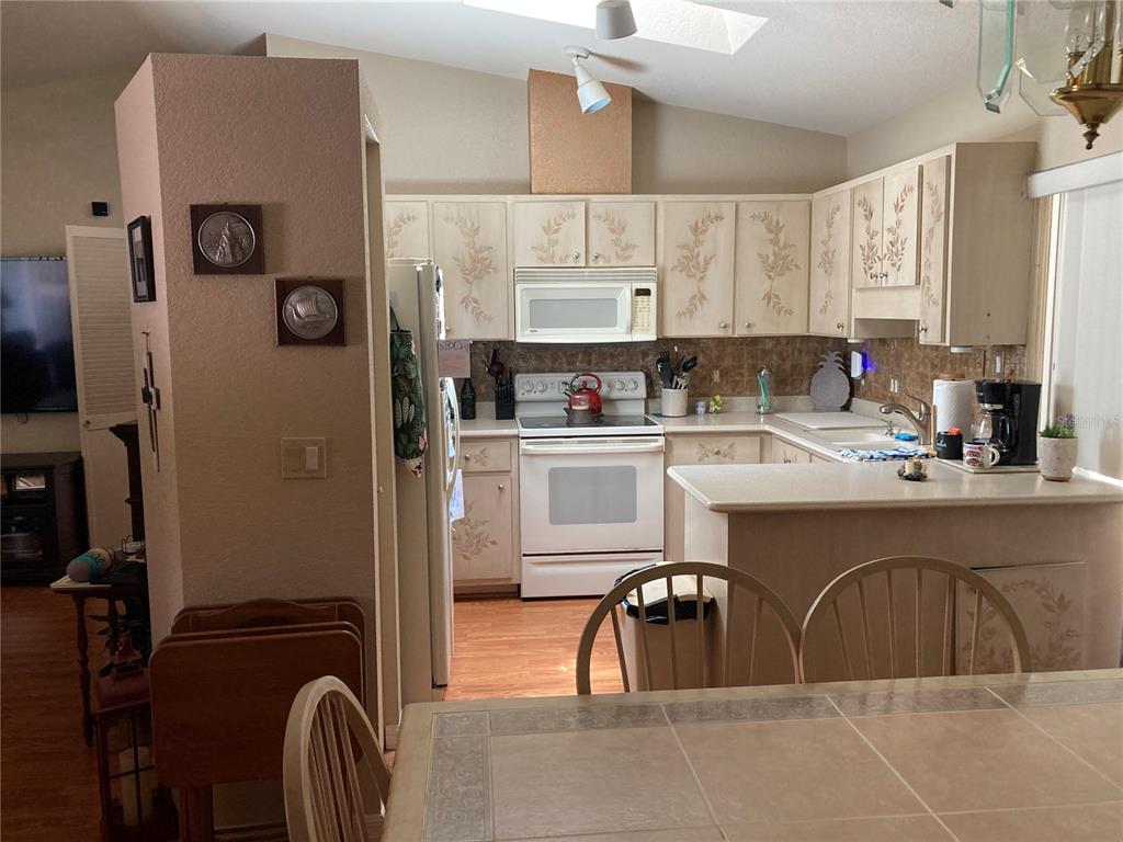 A kitchen with white cabinets featuring floral stenciling, a white stove, and a breakfast bar — 185 CHAMPION STREET, PORT CHARLOTTE, FL