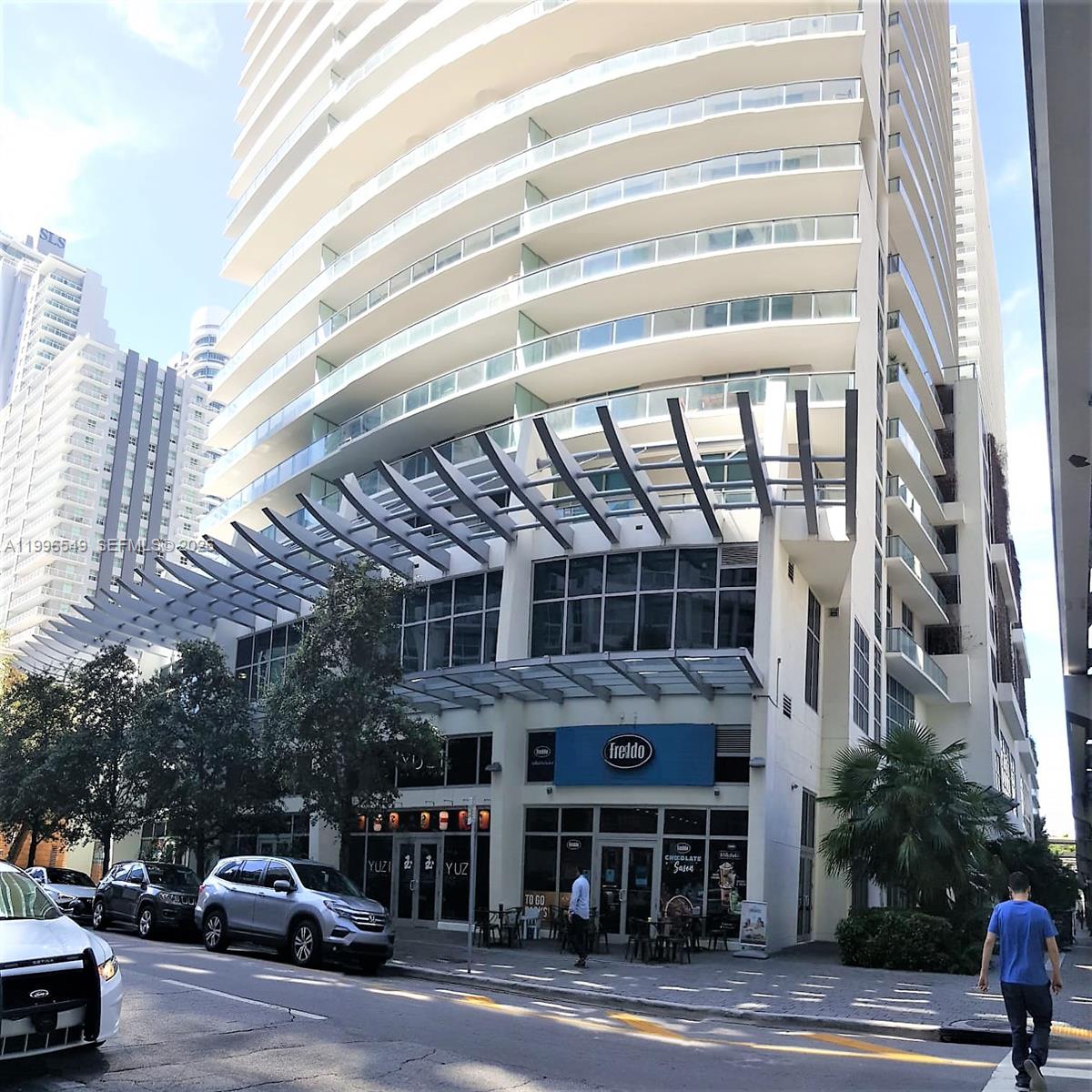 A modern high-rise building features a ground-level storefront with a blue Freddo sign — 1100 S Miami Ave # 1906, Miami FL 33130, MIAMI, FL