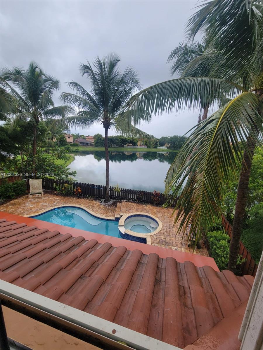 An elevated view shows a swimming pool and spa overlooking a lake with palm trees — 2614 NE 41st Rd, Homestead FL 33033, HOMESTEAD, FL