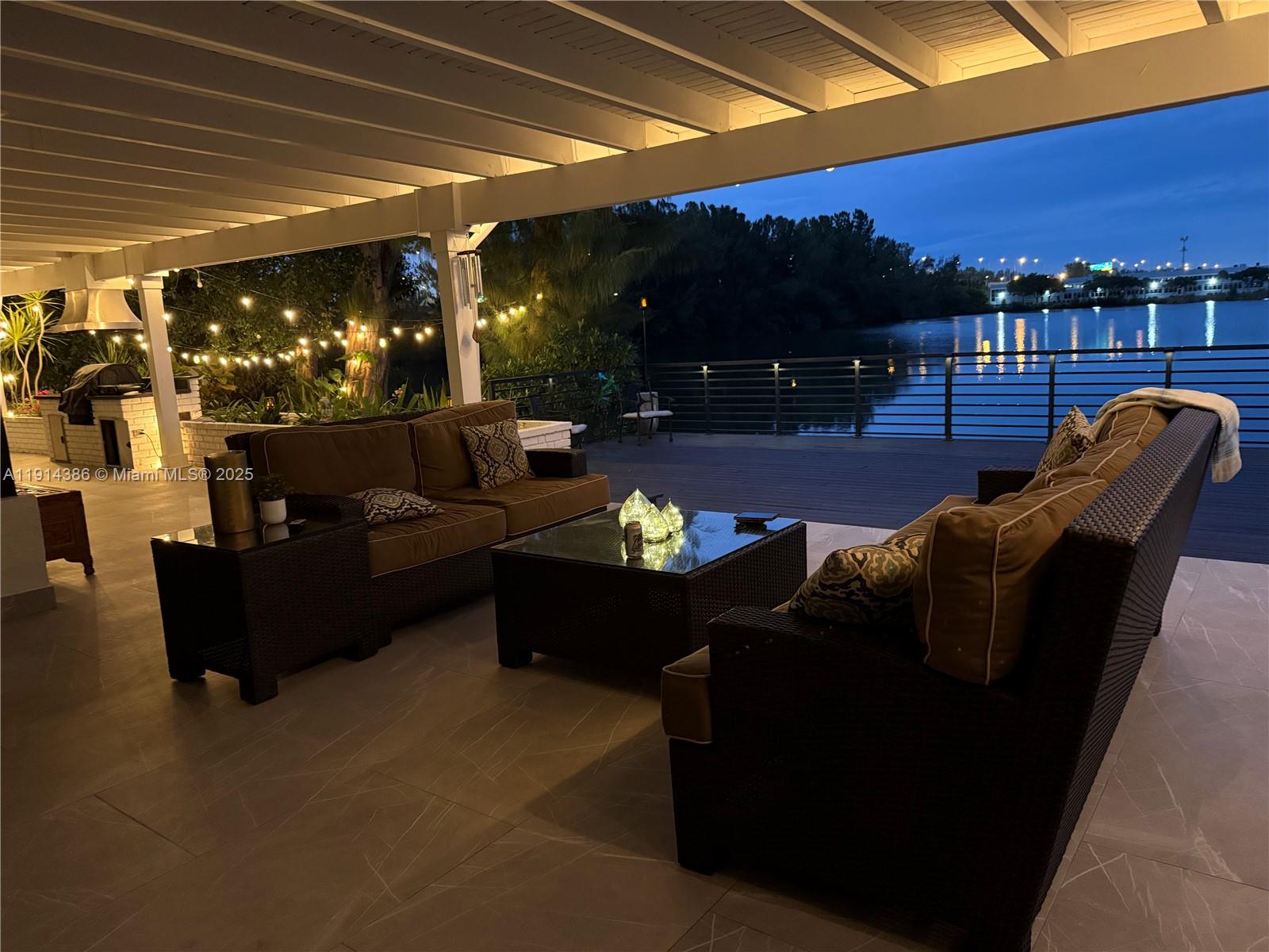 A covered outdoor patio features wicker furniture, a coffee table, and a waterfront view — 7521 SW 56th St, Miami FL 33155, MIAMI, FL