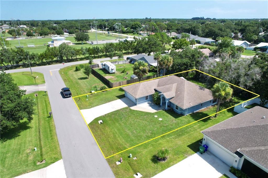 An aerial view shows a single-story house with a driveway and yard outlined in yellow — SEBASTIAN, FL