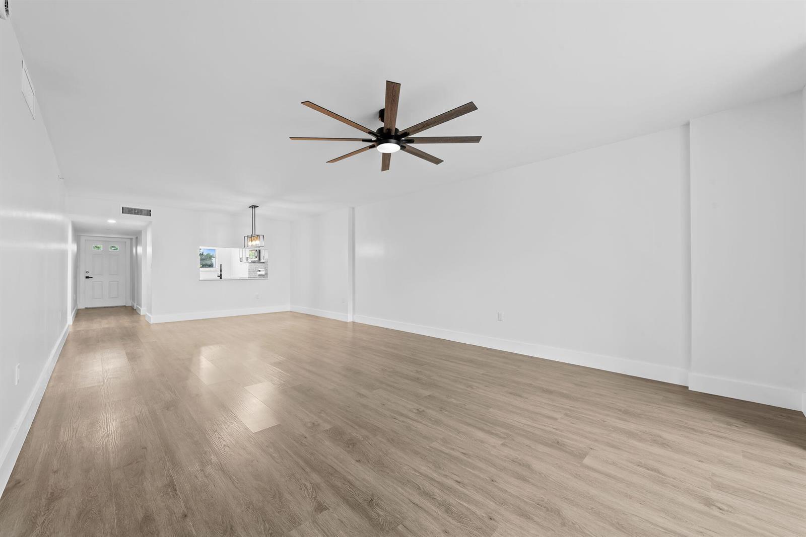 An empty living room features light wood-look flooring, white walls, and a modern ceiling fan — 4734 E Lucerne Lakes Blvd E # 303, Lake Worth FL 33467, LAKE WORTH, FL