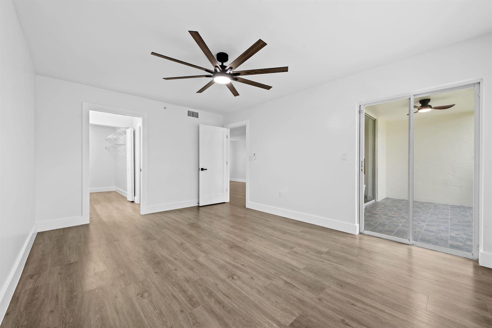 A bedroom with light wood-look flooring, a ceiling fan, and a sliding glass door — 4734 E Lucerne Lakes Blvd E # 303, Lake Worth FL 33467, LAKE WORTH, FL