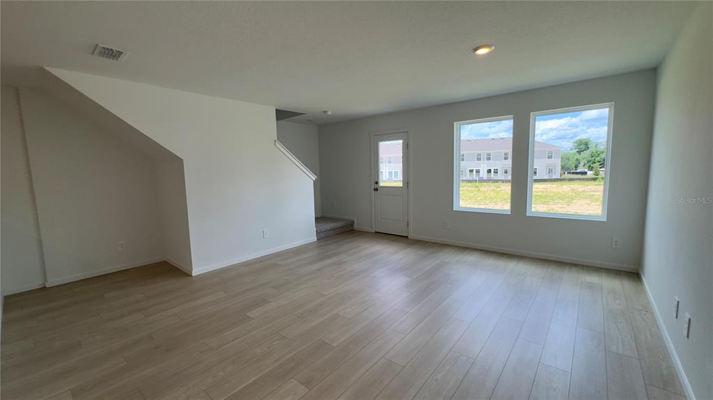 An empty room with light wood-look flooring, white walls, and a door leading outside — 831 LYNX, DAVENPORT, FL