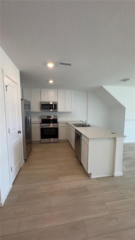 A kitchen features white cabinetry, stainless steel appliances, and a central island with a sink — 831 LYNX, DAVENPORT, FL