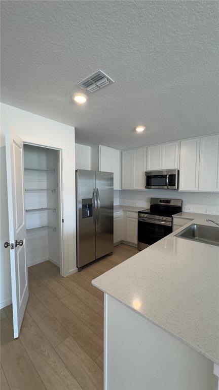 A kitchen with white cabinets, stainless steel appliances, a pantry, and light-colored countertops — 831 LYNX, DAVENPORT, FL
