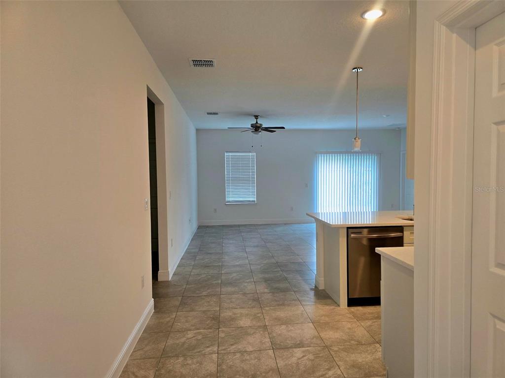 A view from a hallway looking into an open-concept kitchen and living area — 208 LOCUST PASS, OCALA, FL