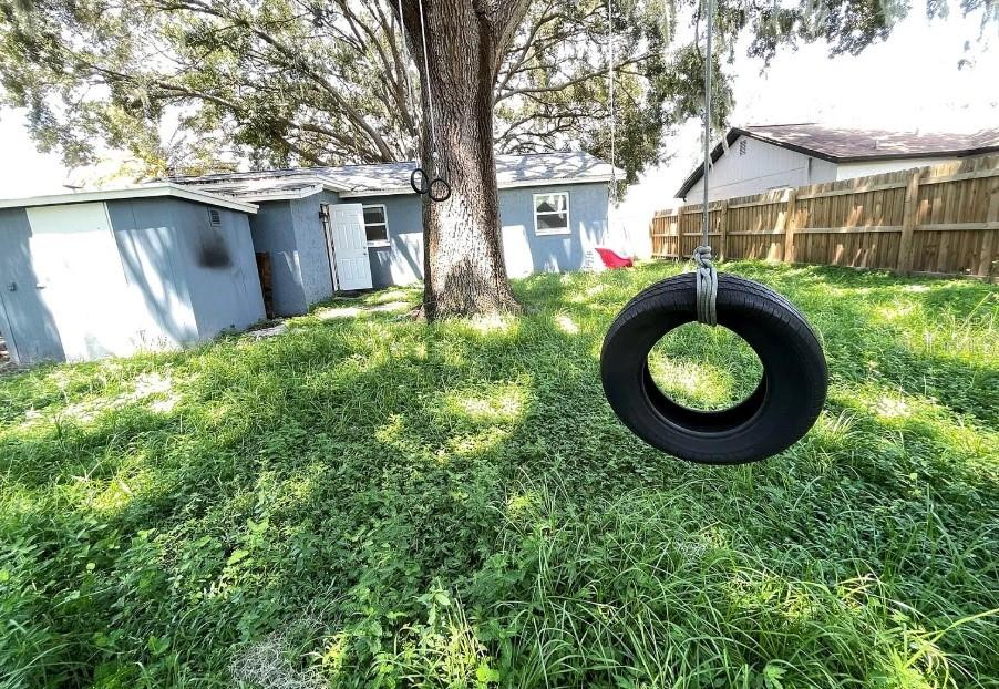 A backyard features a large tree with a tire swing, a shed, and a house — 8104 BADGER LANE, NEW PORT RICHEY, FL